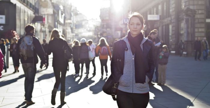 Bild zeigt eine junge Frau in einer Fußgängerzone umgeben von Menschen
