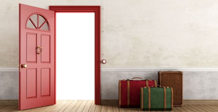 Bild zeigt einen leeren Raum mit offener Tür und gepackten Koffern